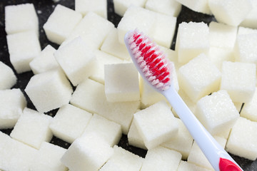 toothbrush on the background of the sugar cubes of refined sugar, preventing tooth decay, caring for the health of your teeth, the causes of caries
