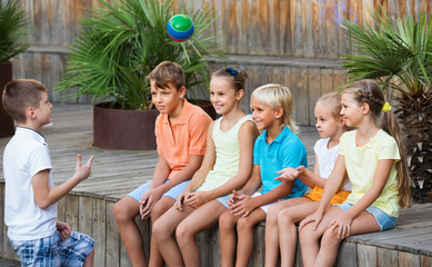 Boys and girls sitting and playing with ball outdoors