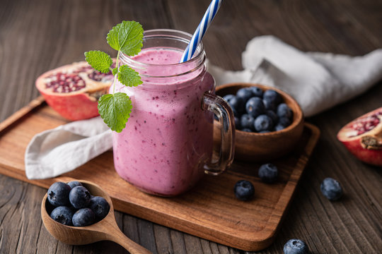 Pomegranate and blueberry smoothie mixed with yogurt and almond milk, served in a glass jar