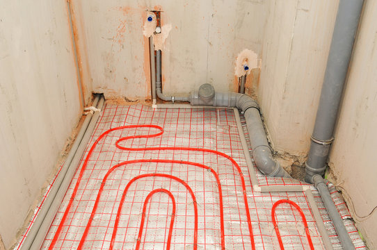 Installation water underfloor heating pipes on the silver reflective material in house construction.