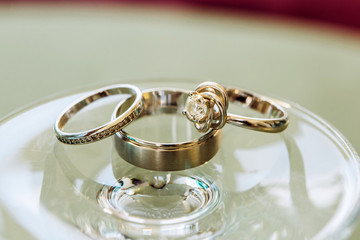 wedding rings with beautiful carvings on a sand background. Three golden rings. Wedding jewelry. Engagement ring.