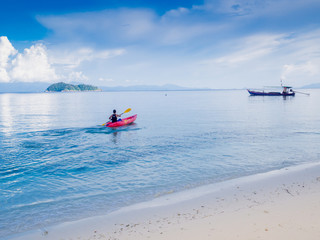 Naklejka premium Man padding red kayak in blue sea at beauty day light, Travel plans in holidays or after retirement
