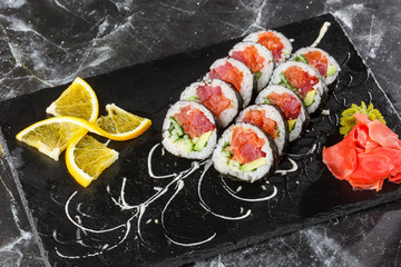 Sushi Rolls with salmon, avocado, tuna and cucumber inside. Maki Futomaki Sushi Rolls with salmon on black marble background . Sushi menu. Japanese food. Horizontal photo.
