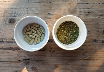 capsule and powder of kratom leaf in white bowl on wooden, kratom leaf (Mitragyna speciosa) Mitragynine, Drugs and Narcotics,Thai herbal which encourage healt