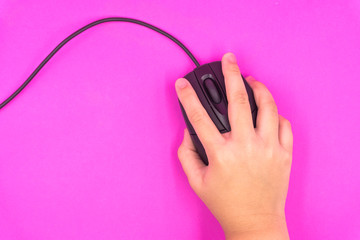 Black wire mouse in kid hand control on isolated pink background