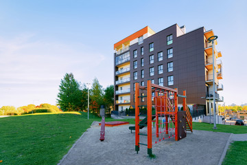 Fototapeta na wymiar Apartment residential house facade architecture with child playground and outdoor facilities. Blue sky on the background.