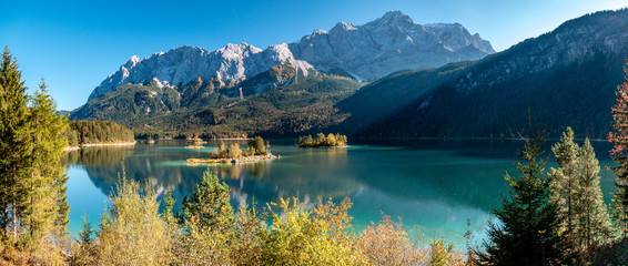 Panorama Image of Eibsee during autumn with the Zudspitze in the background and water reflections