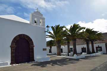Beautiful whitewashed church in Femes Lanzarote with palm trees beyond