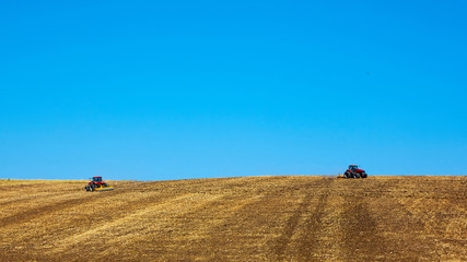 Fototapeta na wymiar Agricultural Landscape. Tractors working on the field.