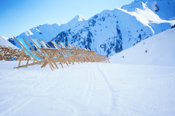 Sun loungers against backdrop of mountains at winter resort