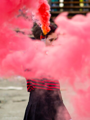Punk rebel girl with colorful pink smoke bomb in her hand on a industreial background. Hipster ultras fan teen vertical shot