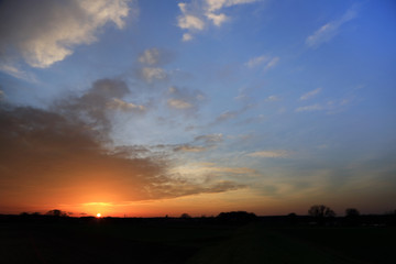 Fototapeta na wymiar Złoty i pomarańczowy zachód słońca na obszarze wiejskim.