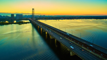 Fototapeta premium Automobile and railroad bridge in Kiev, the capital of Ukraine. Bridge at sunset across the Dnieper River. Kiev bridge against the backdrop of a beautiful sunset in Kiev. Bridge in evening sunshine