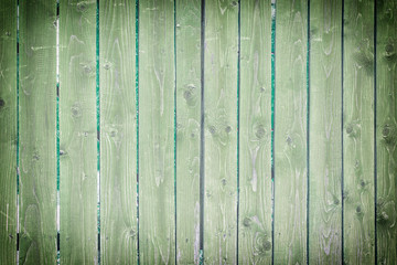 Old wooden fence of green color. Background with texture of vertical boards. Photo with vignette.