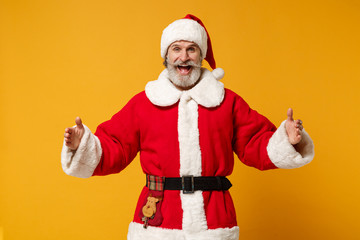 Elderly gray-haired bearded mustache Santa man in Christmas hat posing isolated on yellow background. New Year 2020 celebration concept. Mock up copy space. Demonstrate size with horizontal workspace.