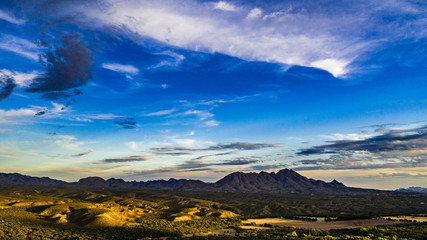 Naklejka na ściany i meble Sunset, aerial landscapes of Santa Rita Mountains from above Tubac, Arizona with warm , golden plains, purple mountains, blue sky with colorful clouds on a Fall day 