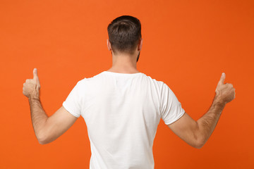Back rear view of young man in casual white t-shirt posing isolated on bright orange wall background, studio portrait. People sincere emotions lifestyle concept. Mock up copy space. Showing thumbs up. - Powered by Adobe