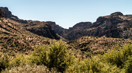 Aerial, landscape along the Salt River in Arizona with pink and orange rocks, purple mountains, cool water, blue sky, cactus, green trees and brush on a Fall day
