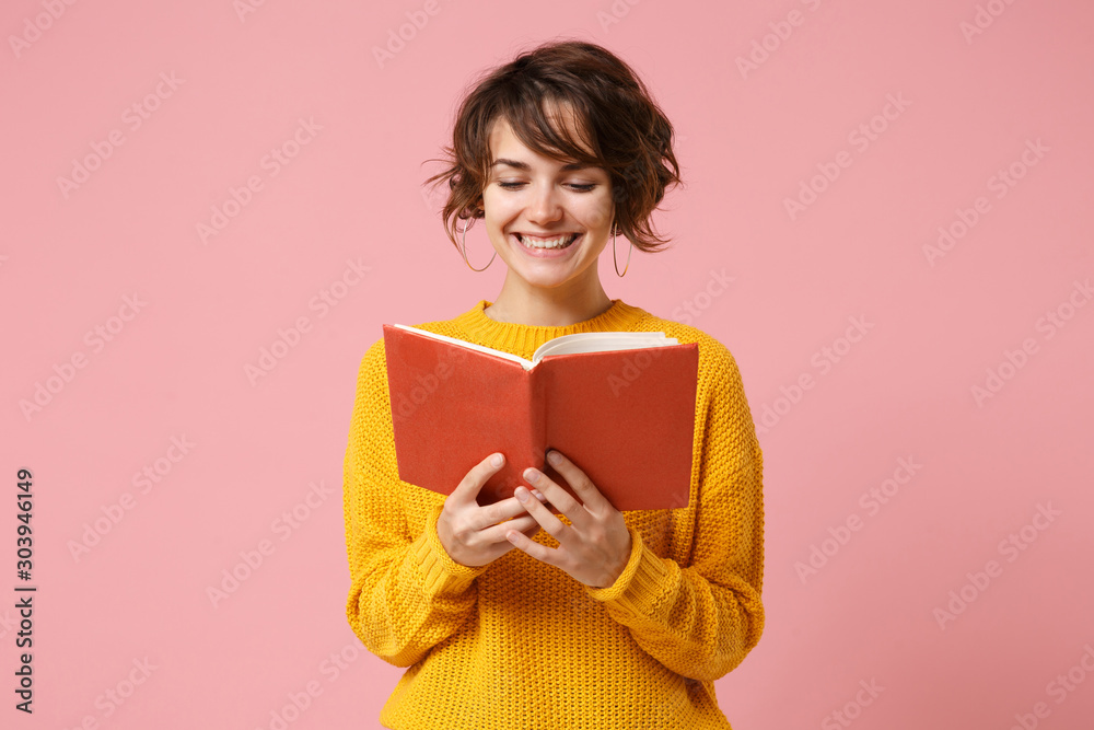 Wall mural smiling young brunette woman girl in yellow sweater posing isolated on pink wall background, studio  - Wall murals