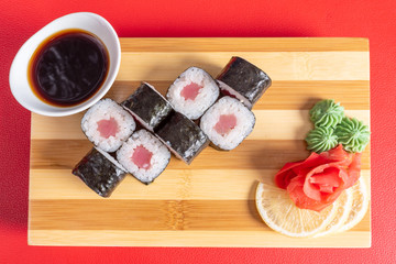 Fototapeta na wymiar Sushi, tuna rolls, On the plank. On a red background.