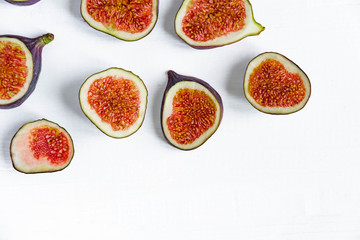 Slices of figs on a white wooden background with a place for inscription. Useful sweets for health. Blank for banner with place for inscription.
