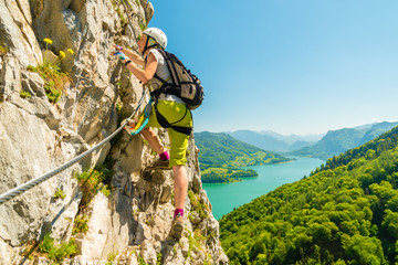 Beautiful young girl climbing Drachenwand via ferrata above scenic Mondsee lake, Alps, Austria, Europe