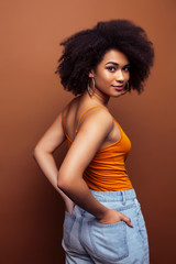 pretty young african american woman with curly hair posing cheerful gesturing on brown background, lifestyle people concept