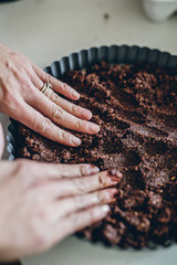 Woman using hands to fill pie crust tin