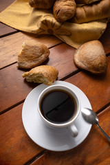 Classic breakfast of Ecuador, served on a wooden table with a cup of coffee and sweet cheese bread, brown sugar, soluble coffee and more bread