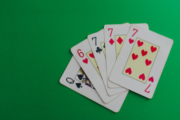 Three of a kind of a seven, cards of a poker deck over a green background