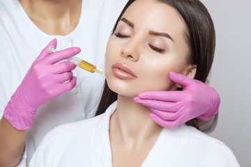 Cosmetologist does prp therapy on the face of a beautiful woman in a beauty salon. There is in...