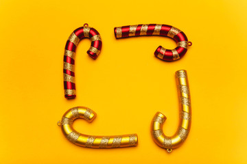 Golden and red frame-shaped Christmas decorations on a yellow background. Festive mood, luxury party, winter holidays. Copy space.