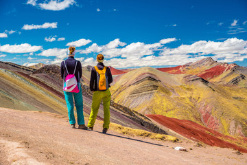 Girls watching stunning view at Palccoyo rainbow mountain (Vinicunca alternative), mineral colorful stripes in Andean valley, Cusco, Peru, South America