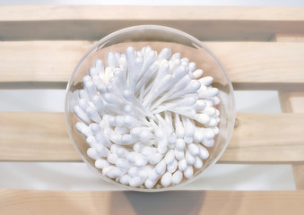 SPA set of cotton buds in a transparent glass on a grate of natural wood in a vapor atmosphere