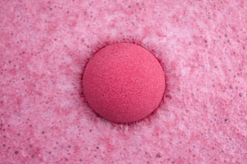 Pink bath bomb foaming in water