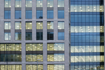 Fototapeta na wymiar illuminated windows on the facade of a large modern office building with lights turned on on at twilight