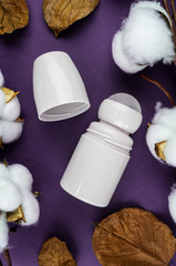 Mockup antiperspirant on a purple background. Cotton and leaves are natural cosmetics.