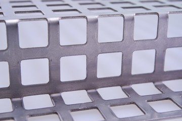 Perforated stainless metal sheet on white background.