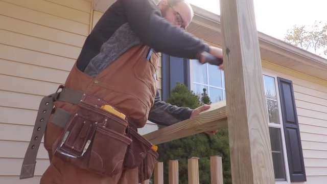 Carpenter hammering wood into place on a porch