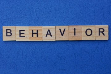 word behavior made from brown wooden letters lies on a blue table  