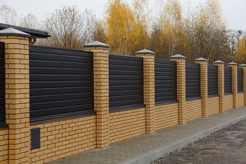 long private fence of brown planks and bricks on a rural street