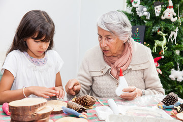 Grandmother teaching her granddaughter how to make christmas Nativity crafts - Real family