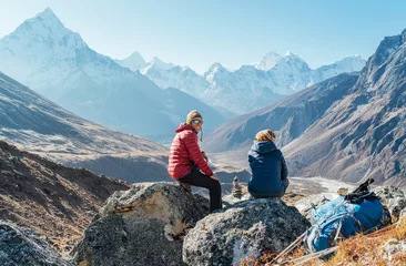 Papier Peint photo autocollant Ama Dablam Cute Couple resting on the Everest Base Camp trekking route near Dughla 4620m. Man smiling to woman.Backpackers left Backpacks and trekking poles and enjoying valley view with Ama Dablam 6812m peak