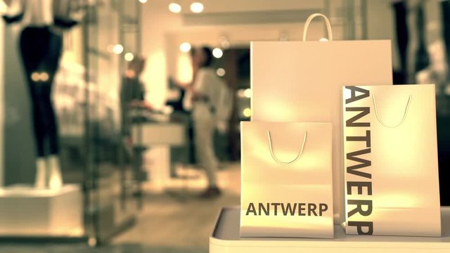 Shopping bags with Antwerp caption against blurred store entrance. Shopping in Belgium related 3D animation
