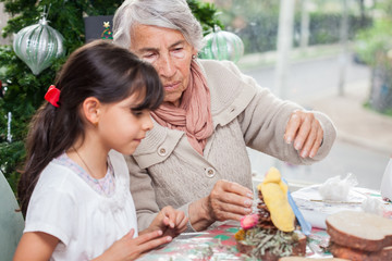 Fototapeta premium Little girl having fun while making christmas Nativity crafts with her grandmother - Real family