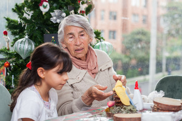 Grandmother teaching her granddaughter how to make christmas Nativity crafts - Real family