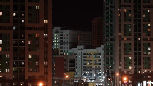 Life in many apartments of multi-storey residential buildings. In the dark, the windows of apartment buildings glow. Night light in the windows of a multi-storey building.