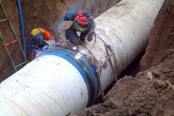 Welders are welding large steel water pipe.