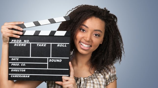 Young woman with movie clapper isolated on white
