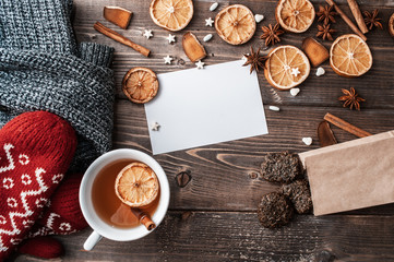 Fototapeta na wymiar winter flatlay with cozy home sweater, mittens, cup of black tea? blank greeting card and spices for mulled wine